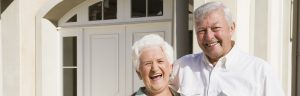 A senior couple outside smiling in front of their home